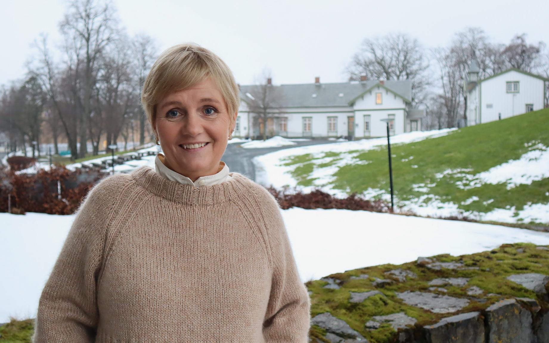 Portrettbilde av kvinne utendørs, i bakgrunnen snø og hvite trebygninger