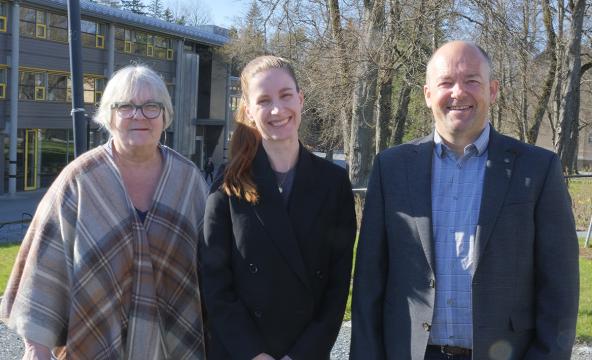 Prodekan forskning, dekan og prosjektleder står foran en av bygningene på campus Levanger.