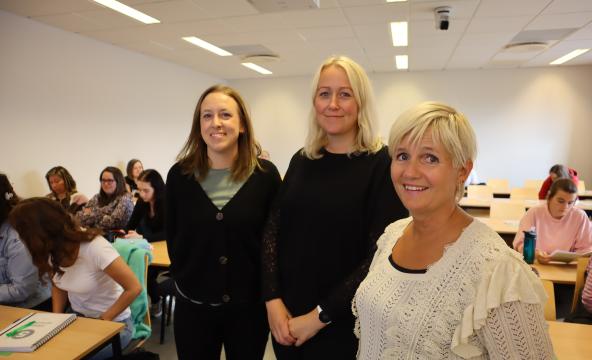 To studenter og leder for barnehagelærerutdanningen smiler