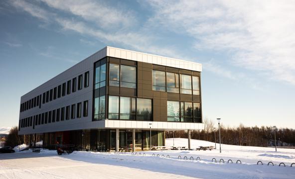 Bygg i snø og under blå himmel. Foto