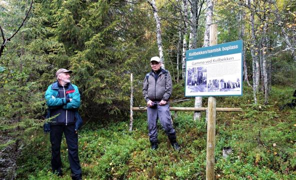 To menn ved et skilt i en skog. Foto