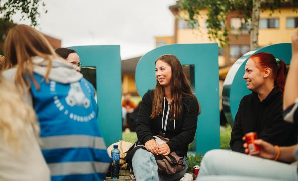 Glade studentar ved studiestart som sit ute. Foto