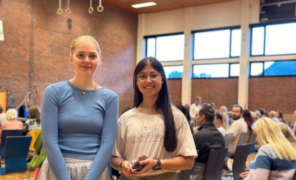 To unge kvinner inne i en aula. Foto