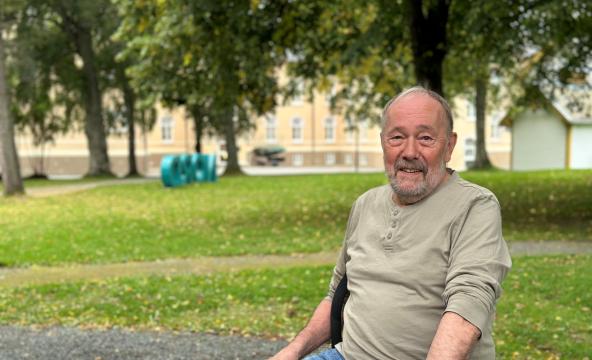 Eldre mann på en benk i en park. Foto