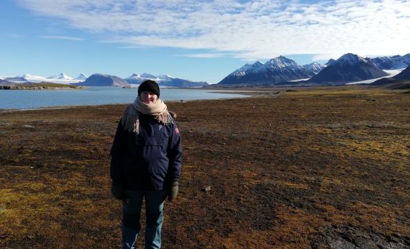 Dame står foran fjell og vann