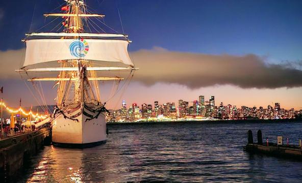 Stor seilbåt i havn med skyline i bakgrunnen