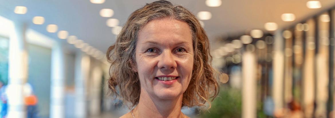 Portrettbilde av en kvinne som står inne i en lys foaje