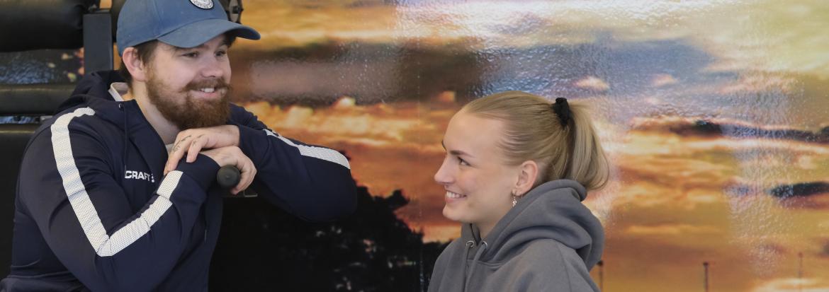 Ung mann og ung kvinne ved fotovegg. Trening, helse og prestasjon. Foto