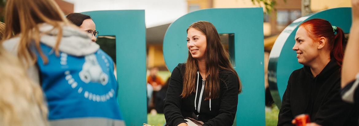 Glade studentar ved studiestart som sit ute. Foto