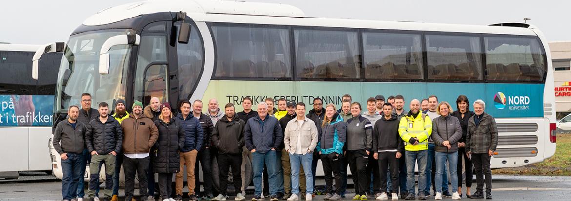 Tretti mennesker foran en buss. Foto