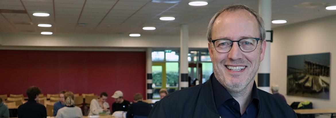 Mann i kantineområde, med folk bak. Veiledningsped. Veiledningspedagogikk. Foto