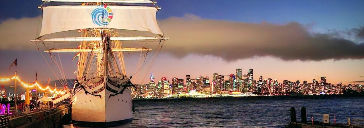 Stor seilbåt i havn med skyline i bakgrunnen