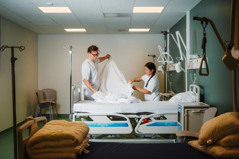 To sykepleiere rer opp sykeseng.