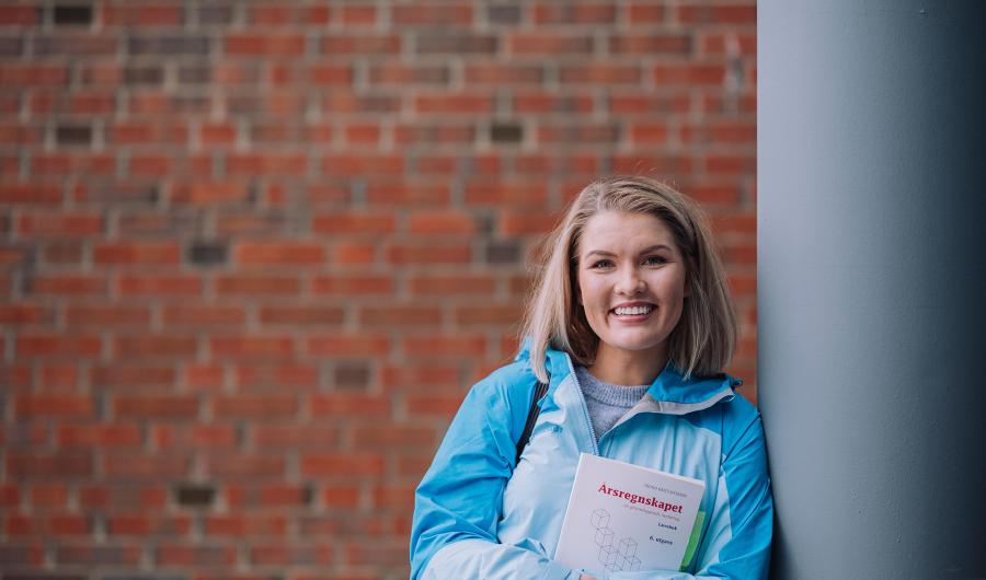 Jente holder bok om årsregnskap