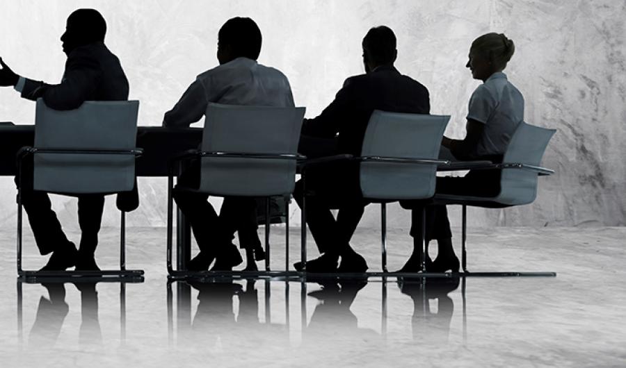 Personer i et møte ved et bord.