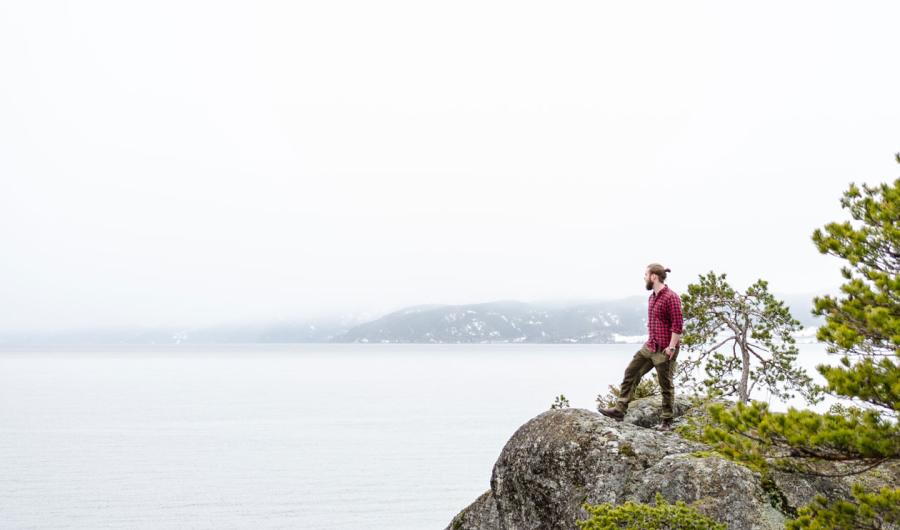 Mann står på et berg og ser utover horisonten