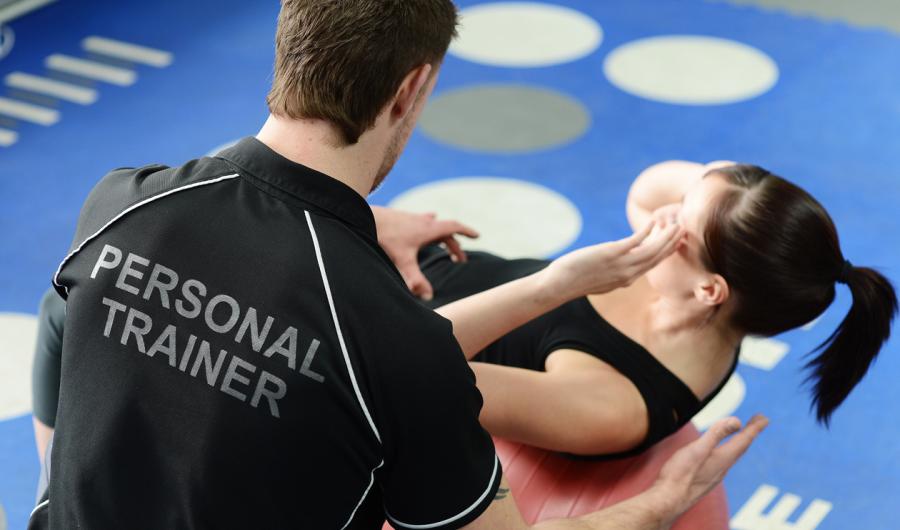 En personlig trener assisterer en person som tar situps.