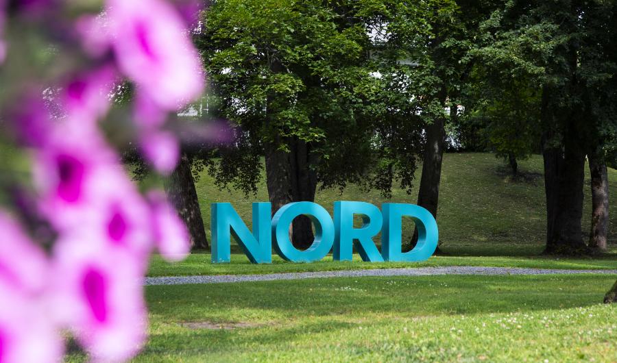 Nord universitet-bokstaver med blomster i forgrunnen