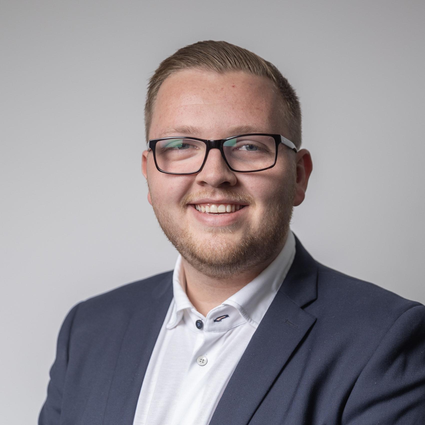 Smilende mann med briller og blå jakke