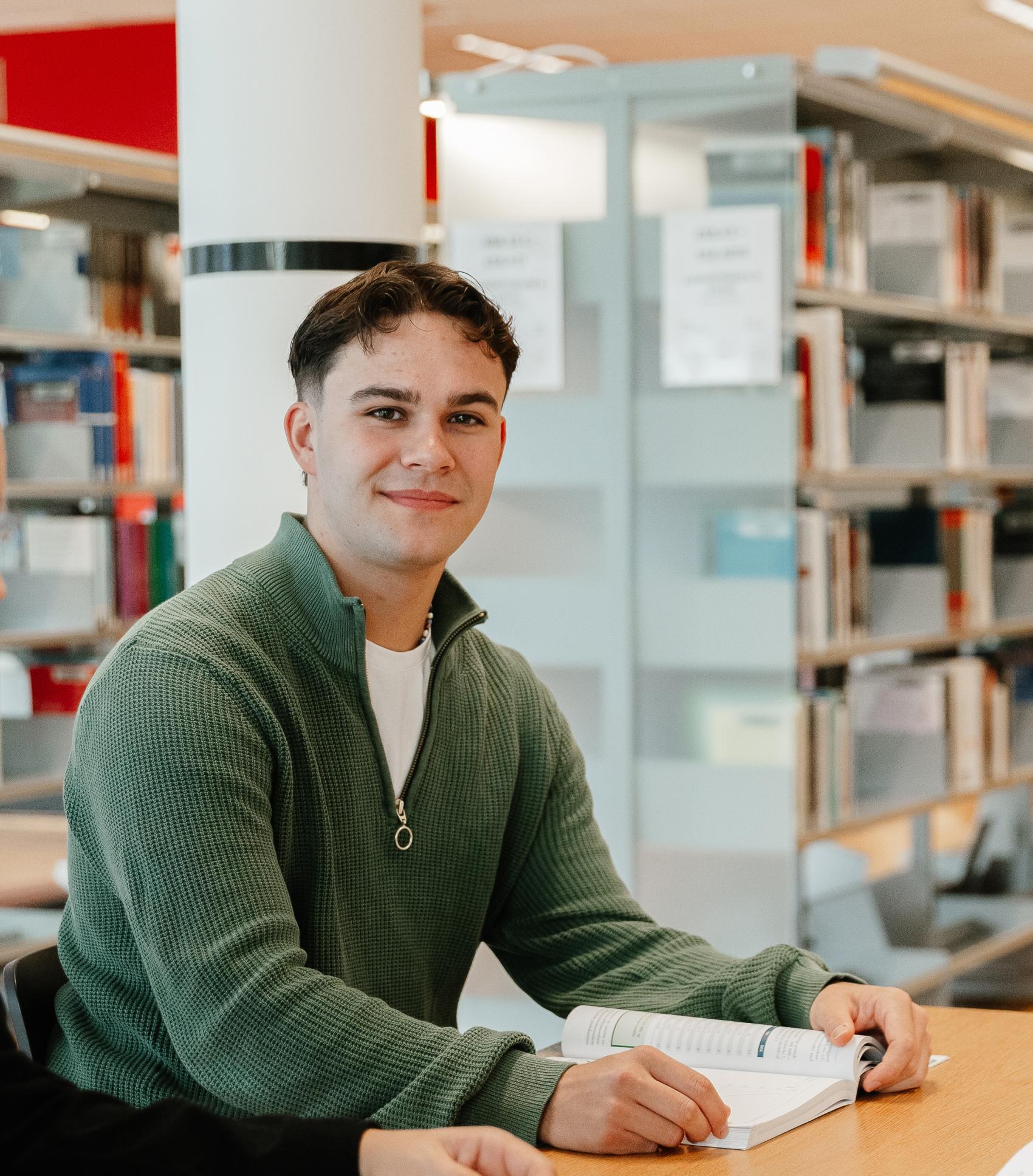 Gutt på biblioteket som ser i kamera