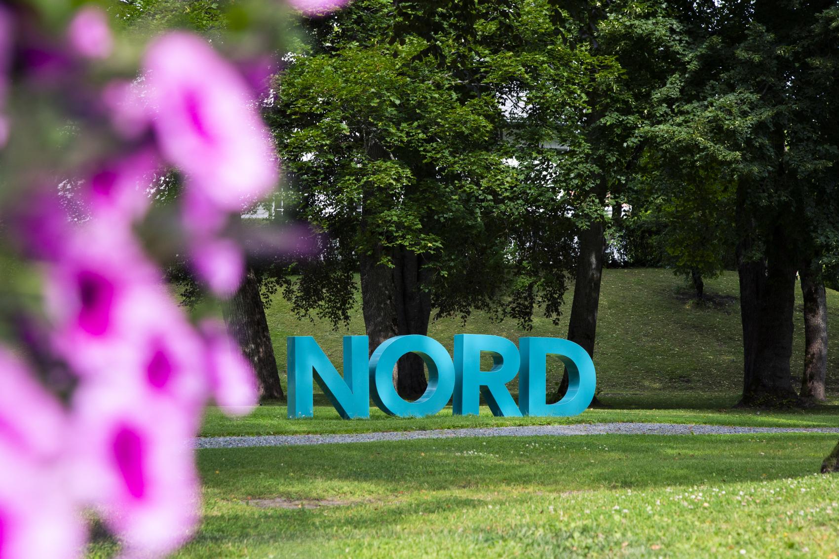 Nord universitet-bokstaver med blomster i forgrunnen