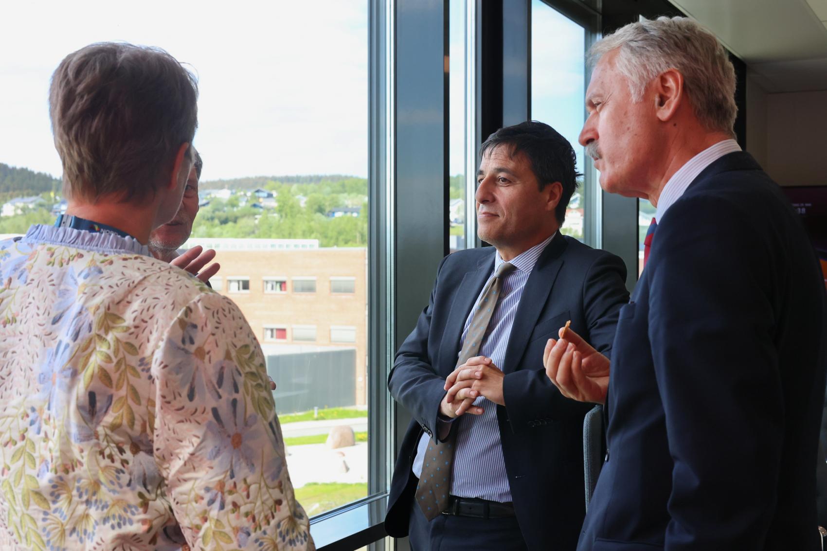 4 people standing by a window, discussing together