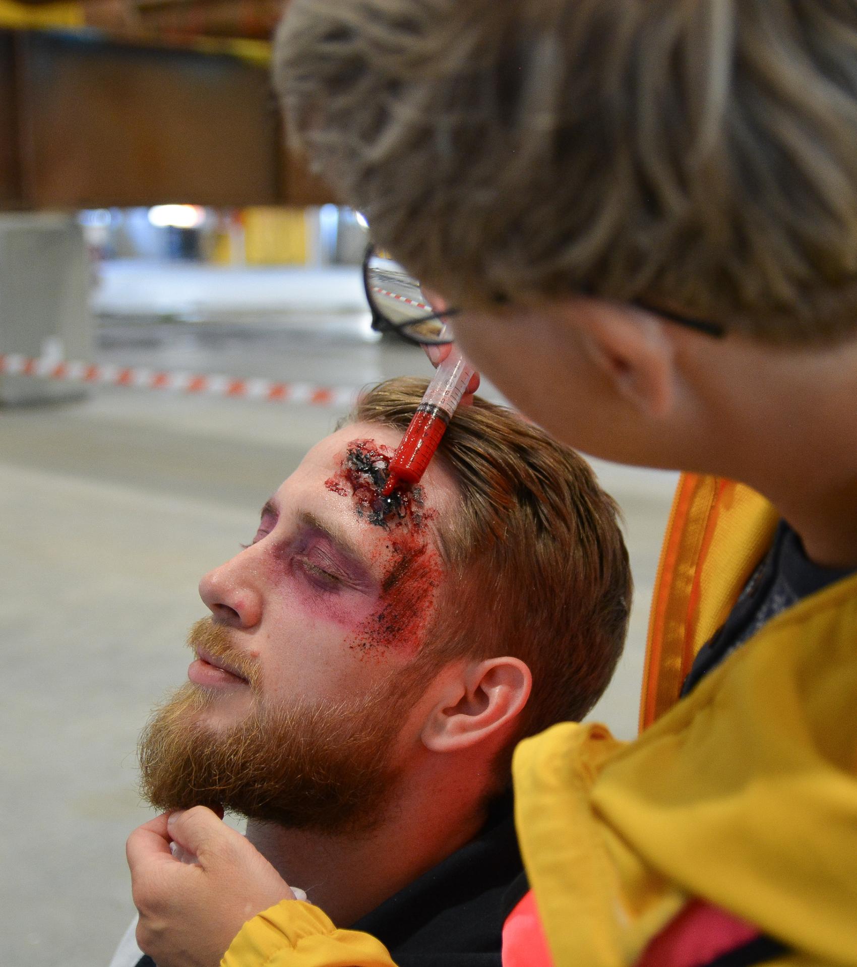 En ung mann blir sminket slik at det ser ut som han har et stort sår i panna og rundt øyet. 
