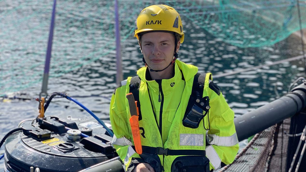 Ung mann i kjeledress ved laksemerde. Foto