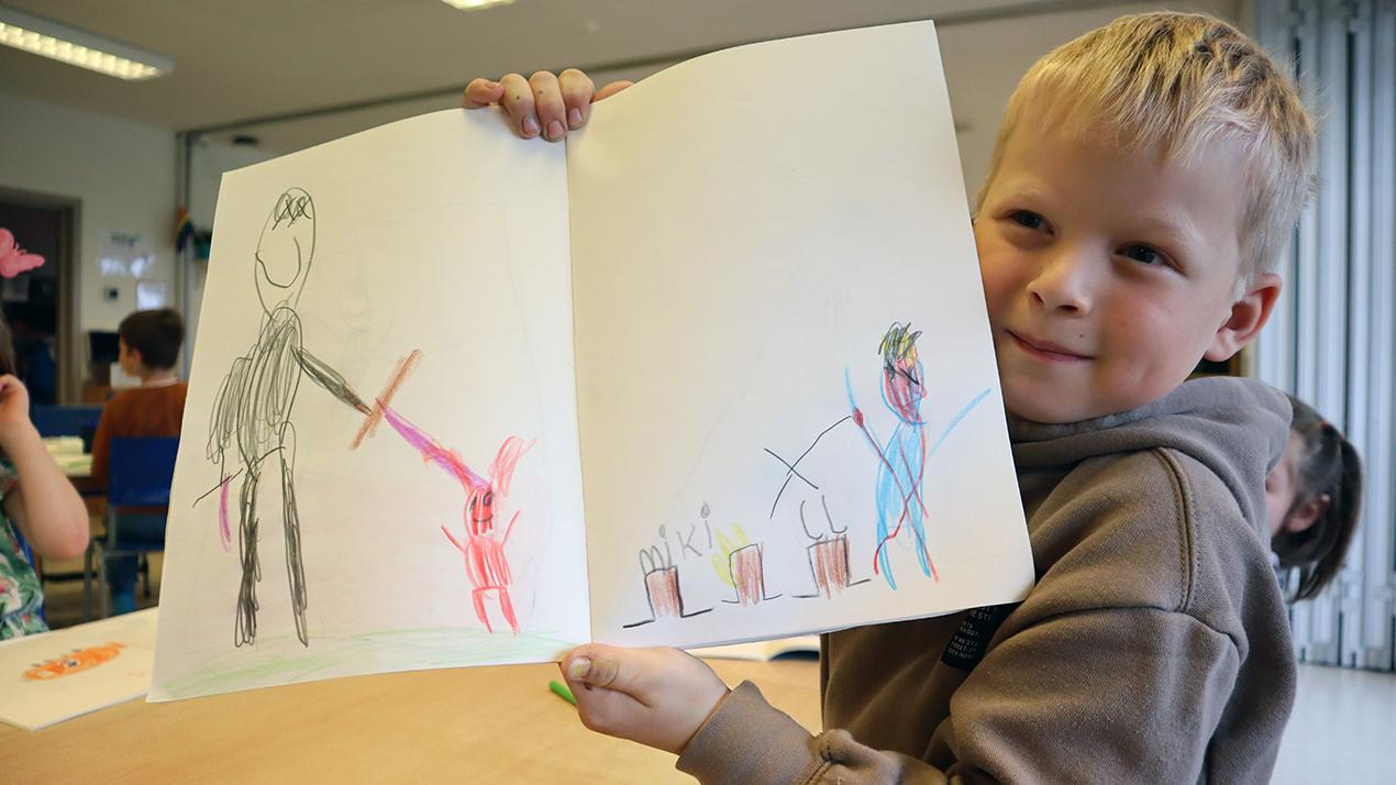 Gutt som held opp ei teikning. Foto