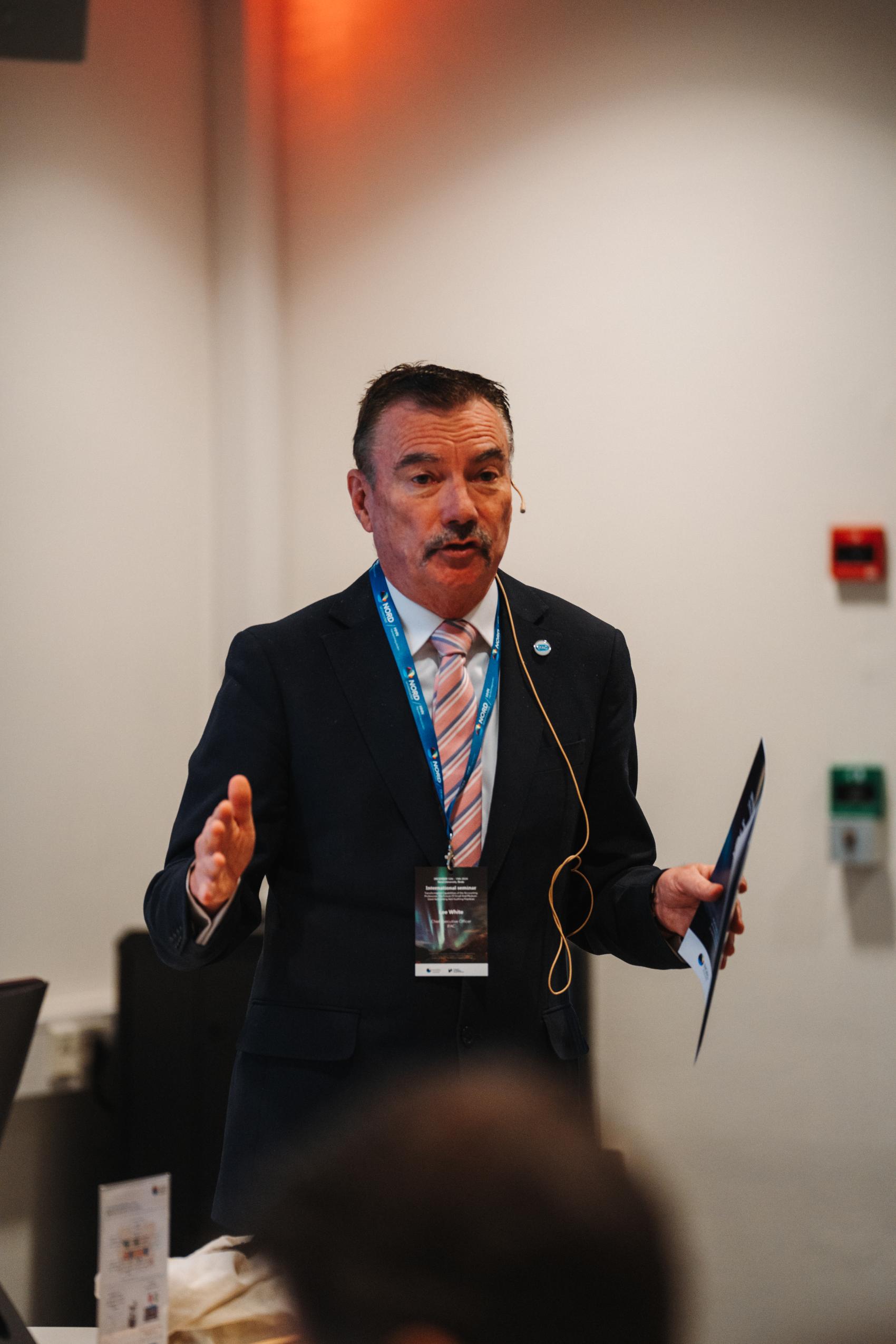 Voksen mann i dress foreleser på seminar.