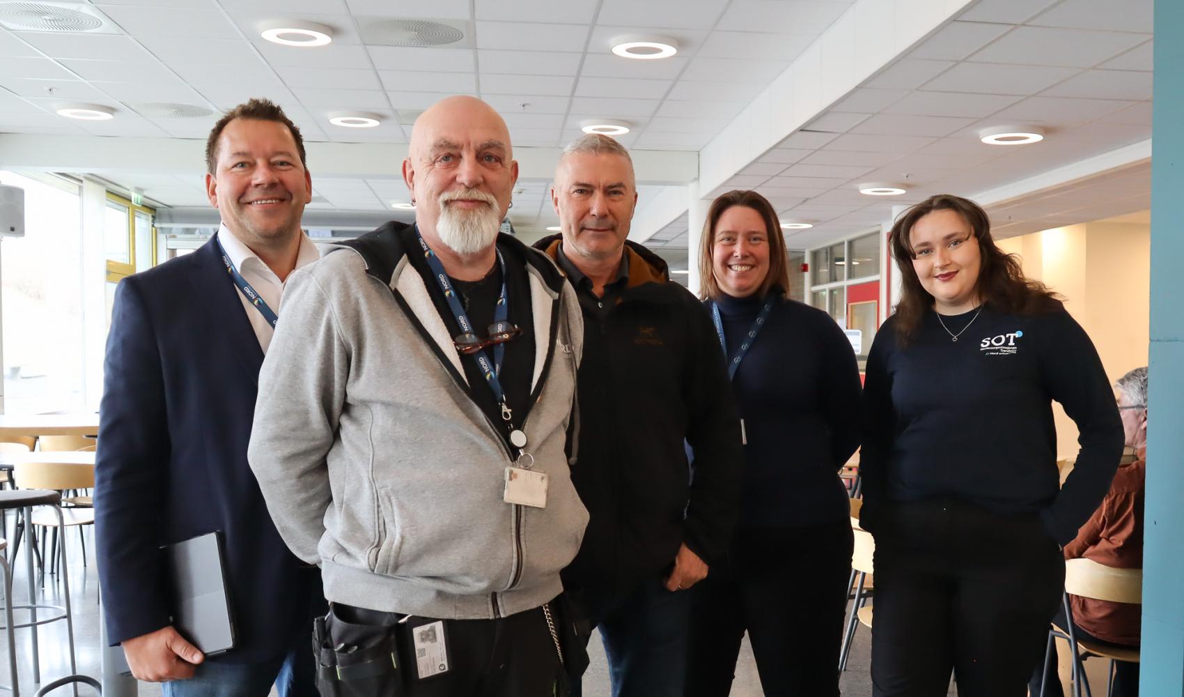 Fem personer, tre menn og to kvinner, oppstilt og smiler til fotografen