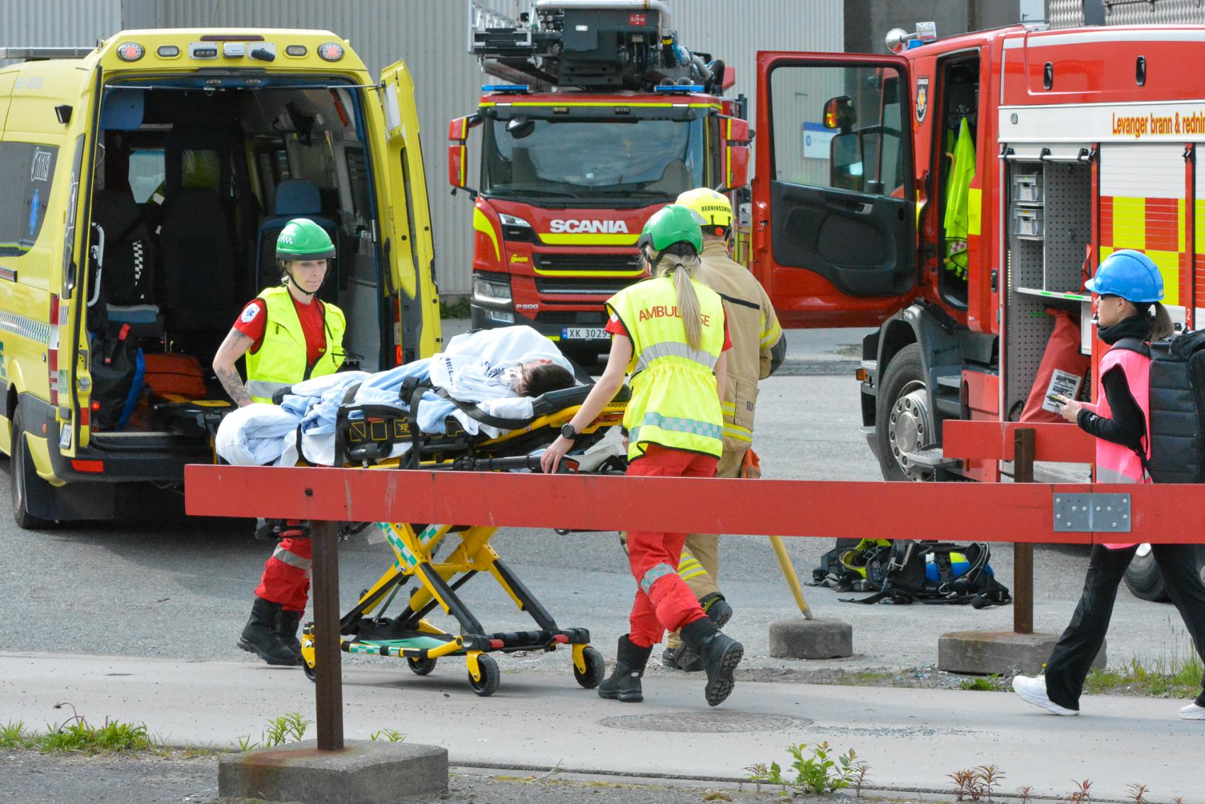 Ambulansearbeidere frakter en pasient på båre til ambulanse