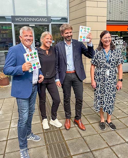 Campusbesøk Vestre, to mannlige politikere og to kvinnelige universitetsansatte ute med bøker i hendene mens de smiler. Foto