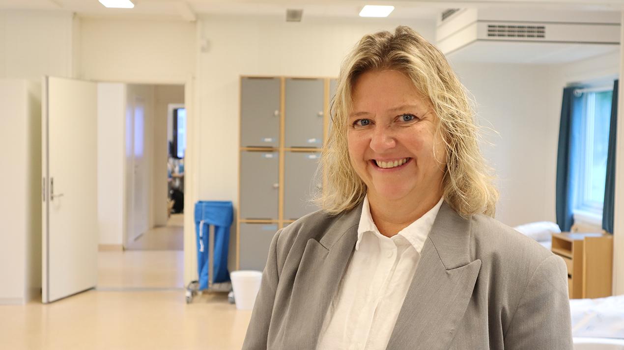 Kvinne med hvit skjorte og grå jakke. Foto