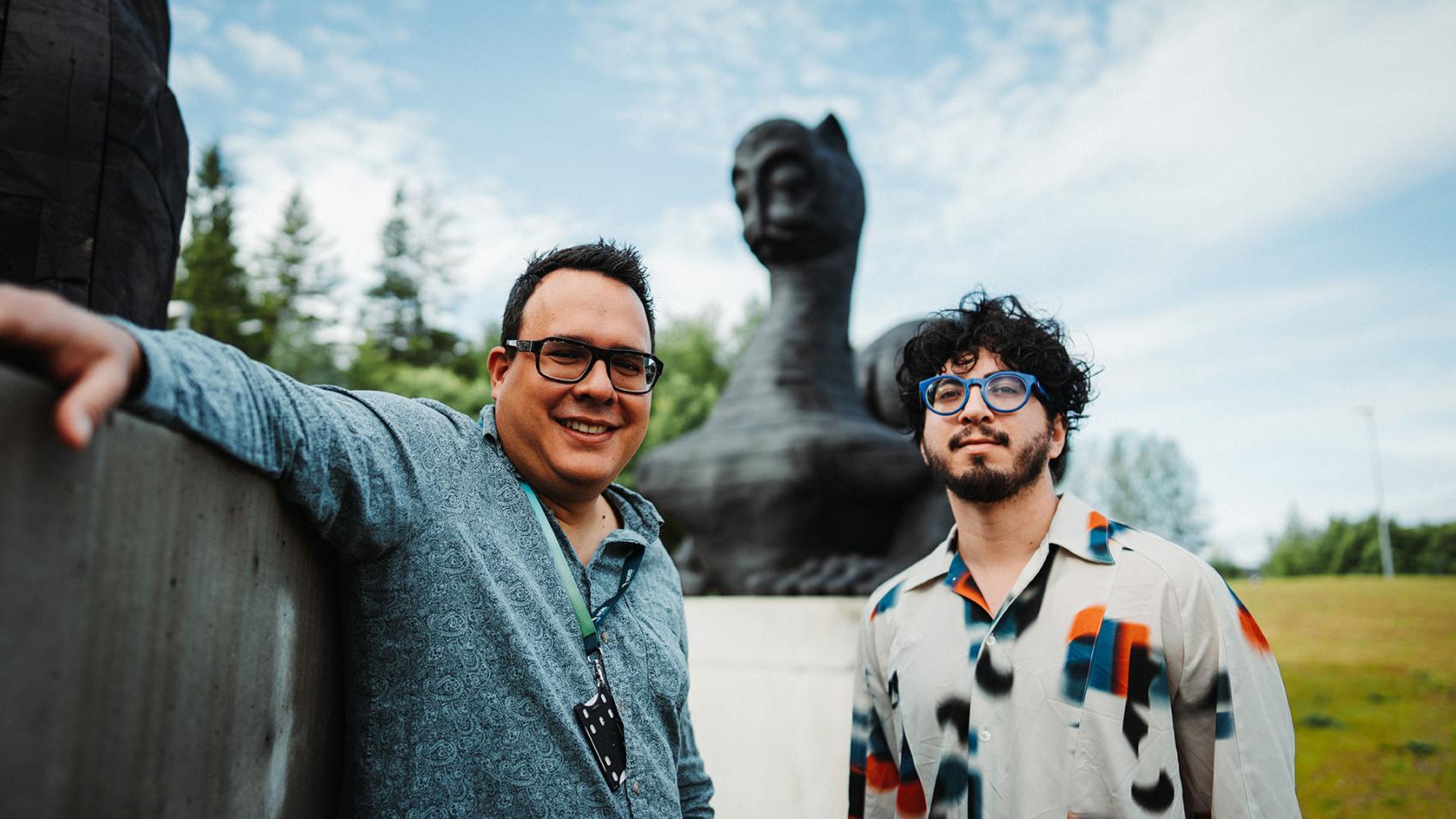 Roberto og Matheus. To menn foran skulptur ute. Foto