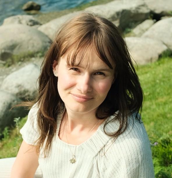 Dame sitter på en plen ved et vann