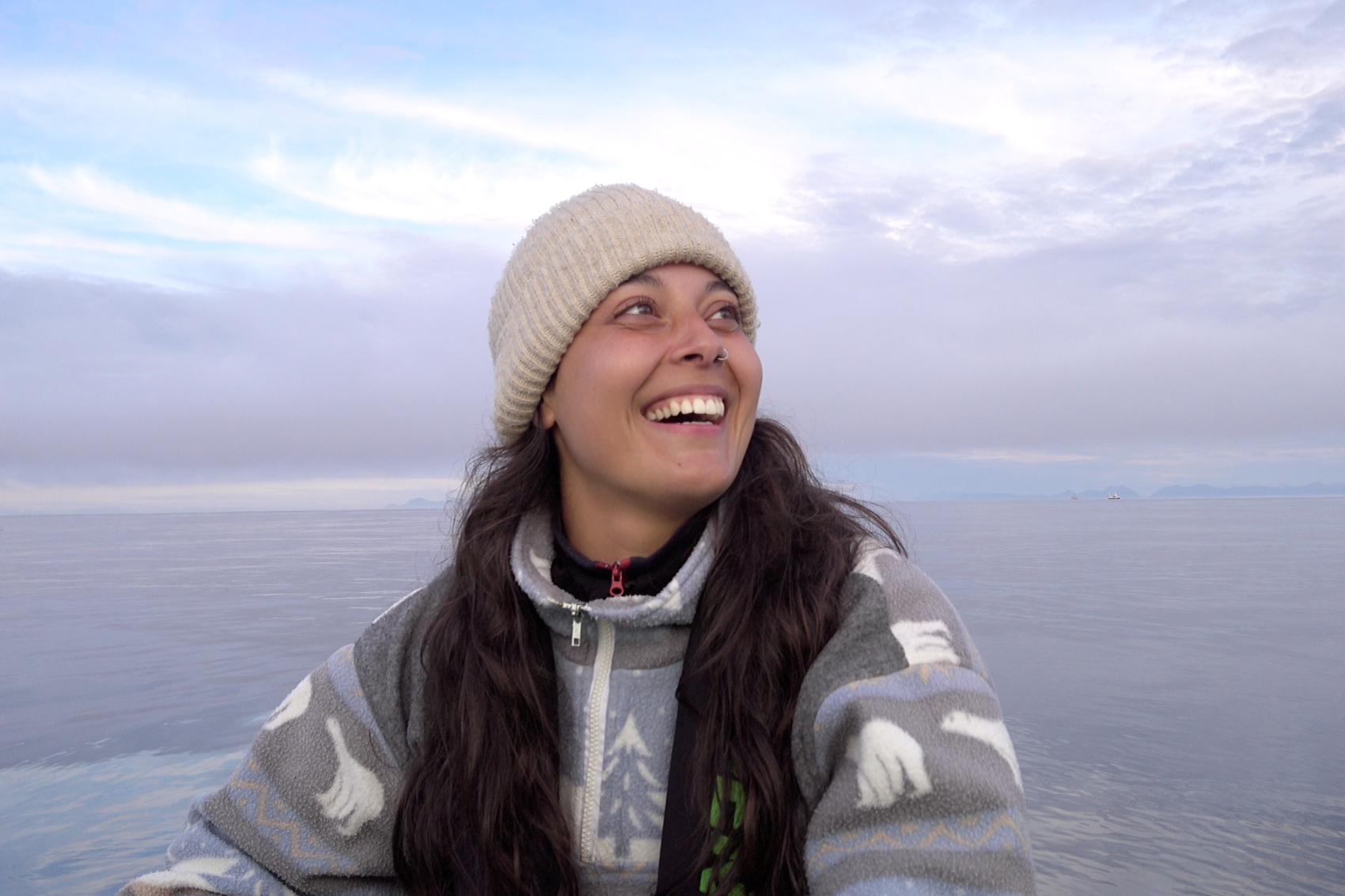 Stipendiat Helena Sofia Gomes Costa ved sjøen i Bodø som ler og ser opp på himmelen