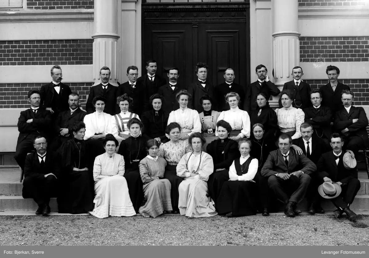 Pent kledde mennesker foran bygning