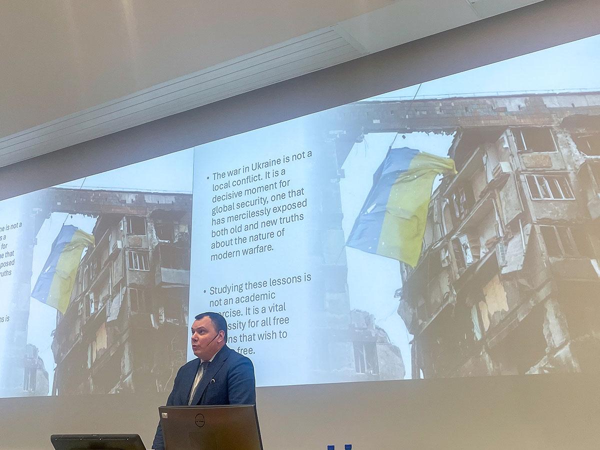 Mann i dress som holder et foredrag. Ambassadør Oleksiy Gavrysh