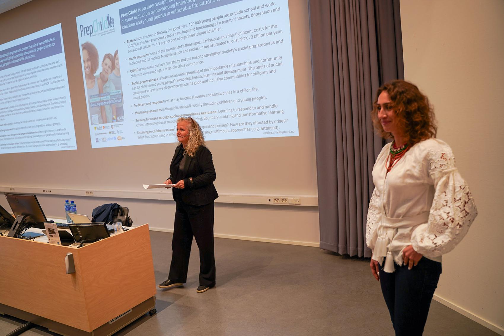 To kvinner foran i en forelesningssal.