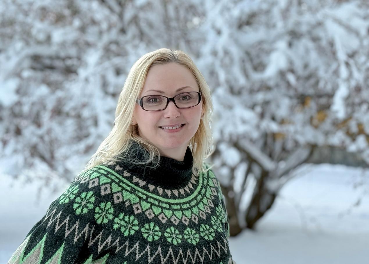 Kvinne i grønn genser ute i vinterlandskap. Foto