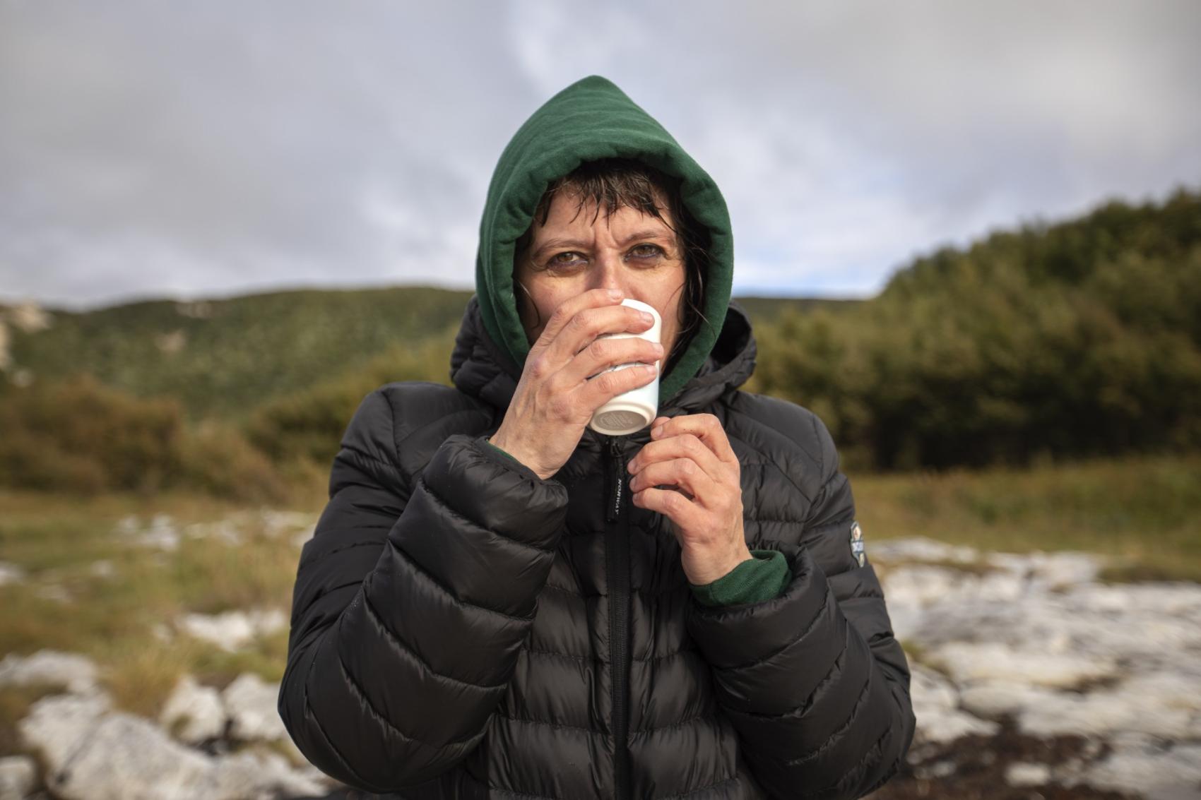Frossen kvinne ute som varmer seg med kaffe og varme klær. Foto