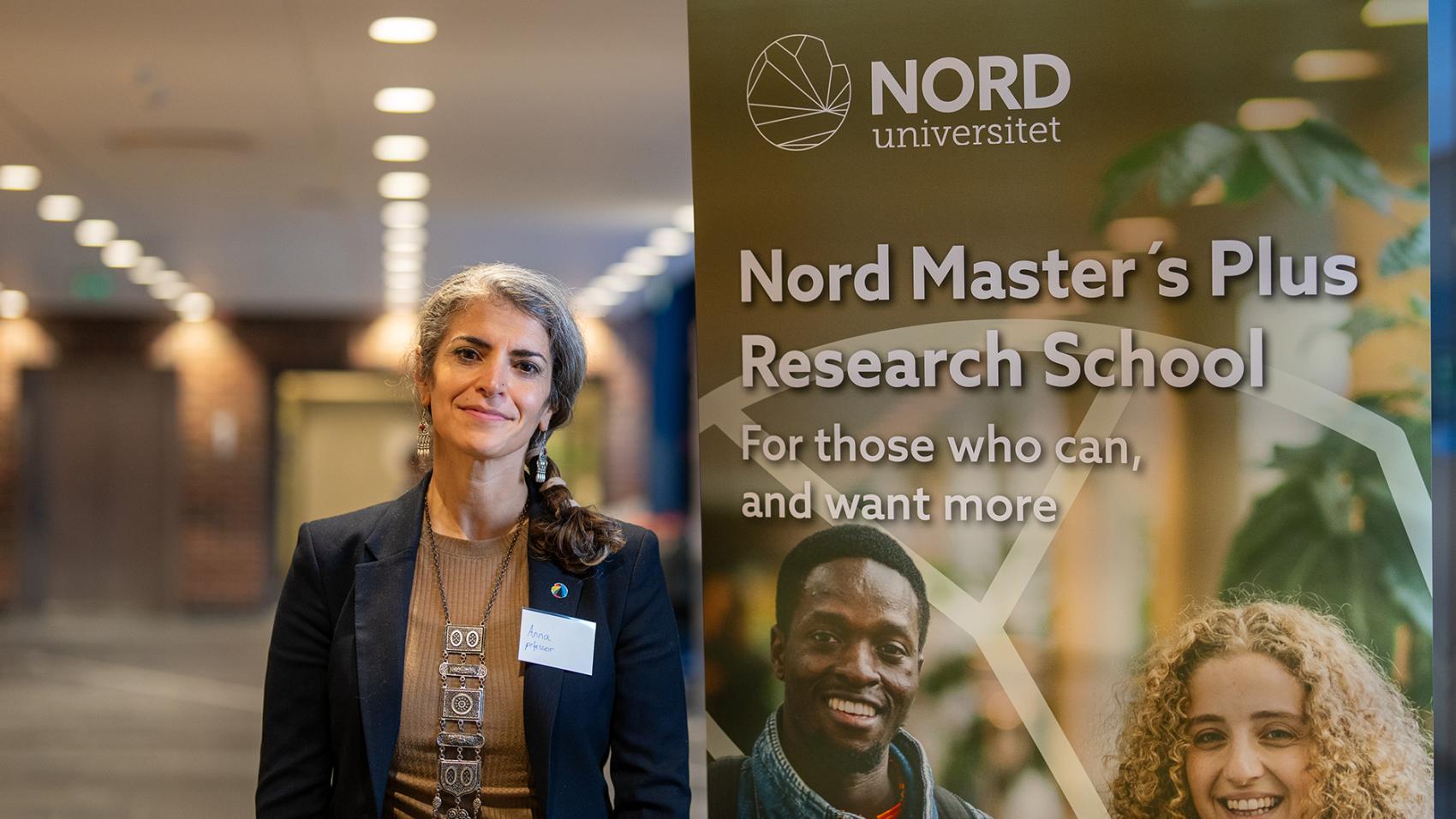 Voksen kvinne inne ved stor rollup. Foto