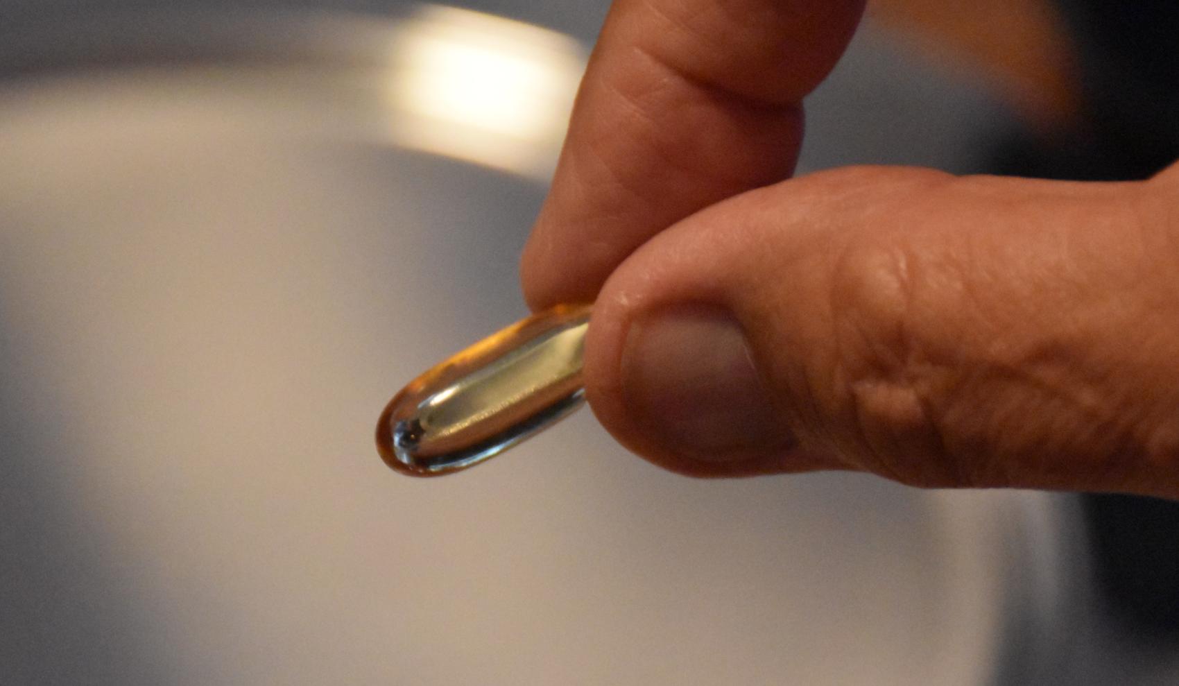 To fingre som holler en pille. Foto