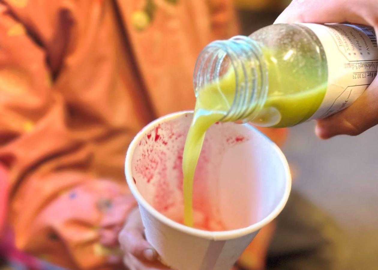 Gul juice som helles fra flaske i kopp