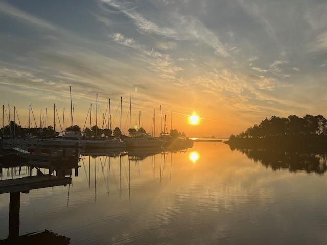 Solnedgang ved fjord med marina og småbåthavn. Foto