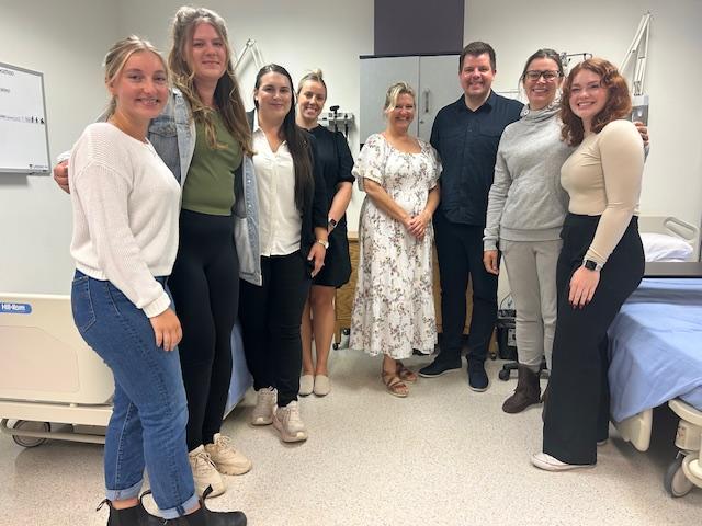 Åtte personer på rekke mellom sjukehussenger. Foto