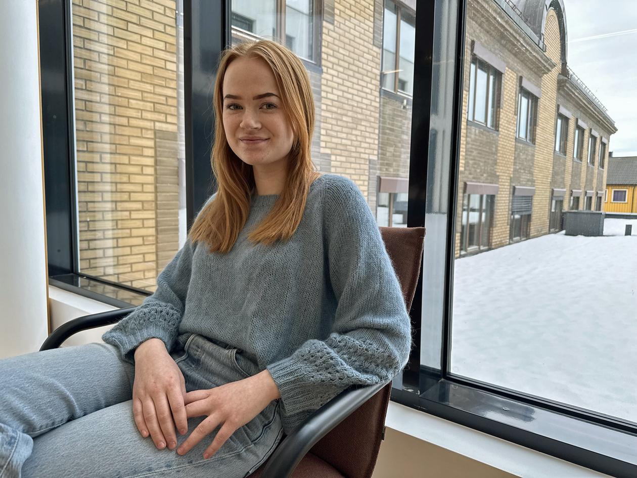 Kvinnelig student i stol foran vindu