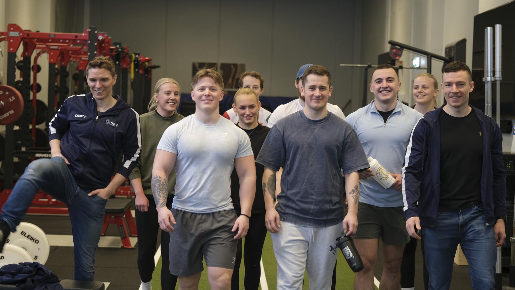 Ti studenter i treningssal. Foto