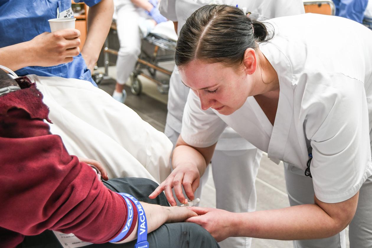 Sykepleierstudent setter kanyle på pasient. Foto